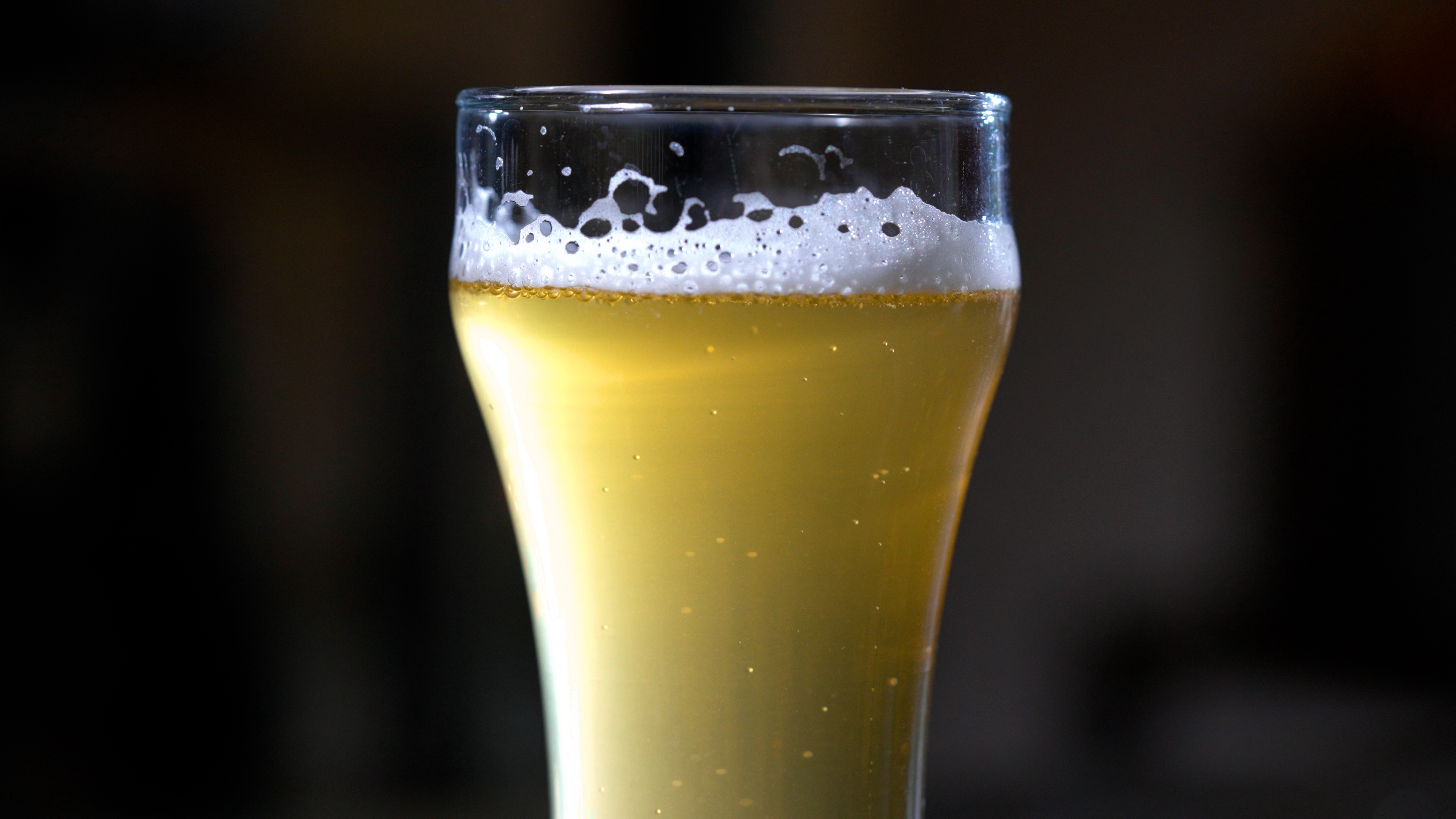 Clear glass filled with light-colored beer and a frothy head.