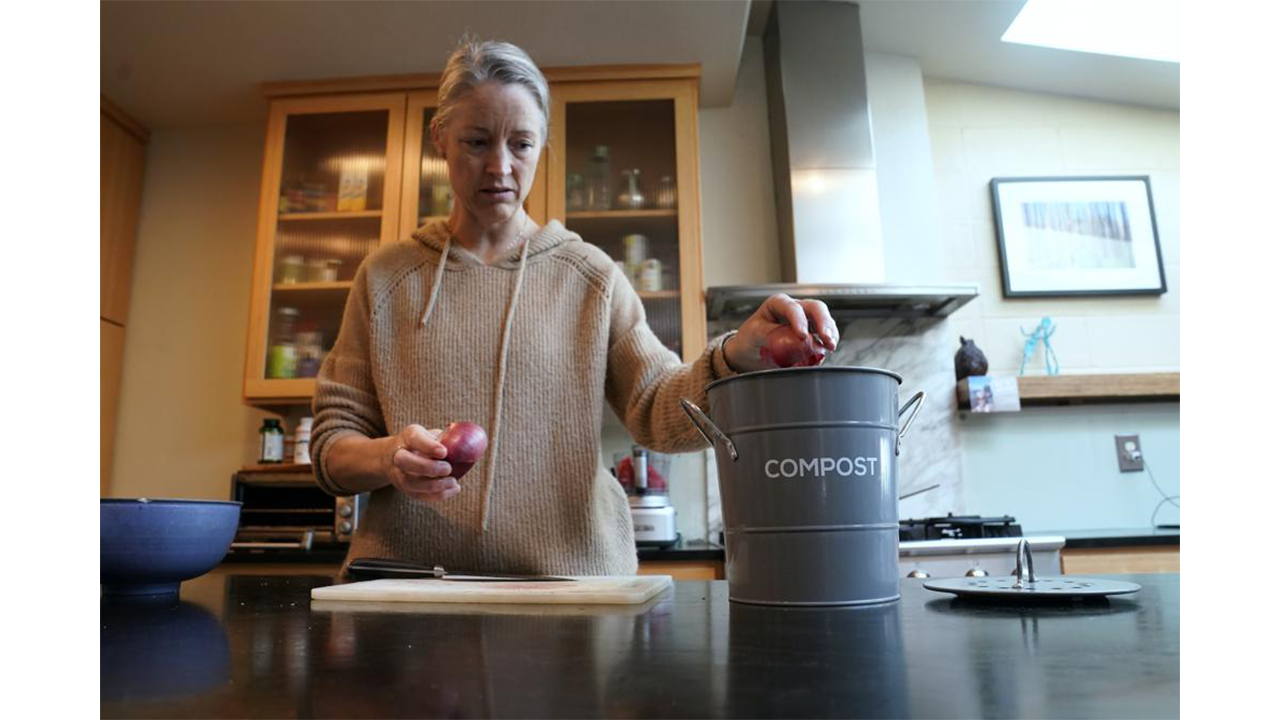Joy Klineberg tosses an onion peel into container to be used for composting while preparing a family meal at her home in Davis, Calif., Tuesday, Nov. 30, 2021. In January 2022, new rules take effect in California requiring people to recycle their food waste to be combusted or turned into energy. Davis already requires residents to recycle their food waste into the yard waste bin instead of the trash. (AP Photo/Rich Pedroncelli) Compost image header AP