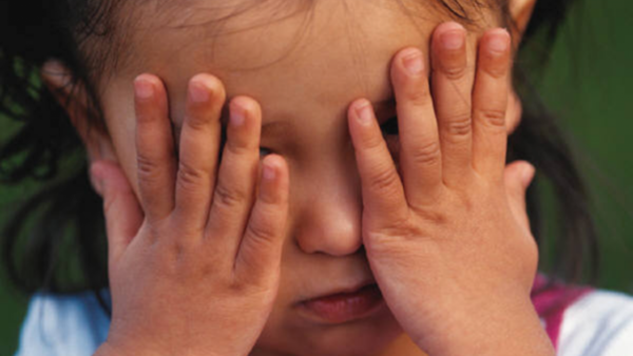 A kid putting her hands on her eyes