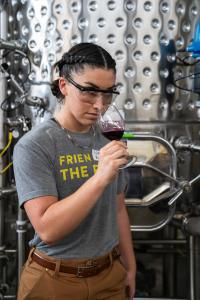 Students smells glass of red wine in front of tank.