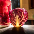 Glass jar of red brine and cabbage next to a cut half-head of red cabbage. 