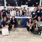 Food Tech Club group picture with students posing together around and in front of a conference table. 